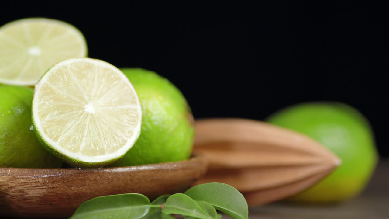 limas frescas con hojas y el exprimidor gira lentamente.