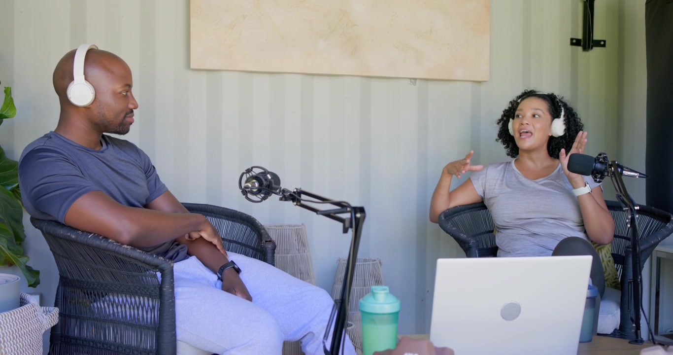 African American co-hosts recording podcast after man's gesture, woman gesturing with boom mic