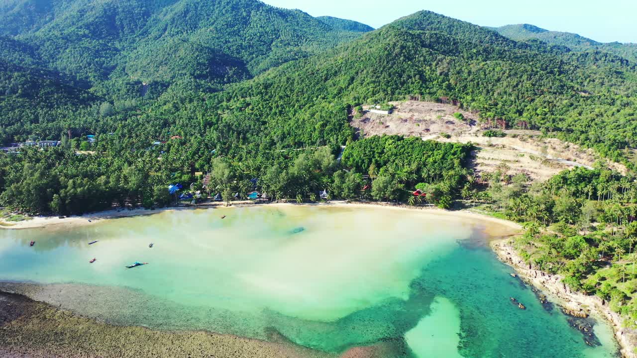 Coral reef barrier surrounding calm clear water of turquoise lagoon near beautiful shore of tropical island with lush vegetation in Thailand