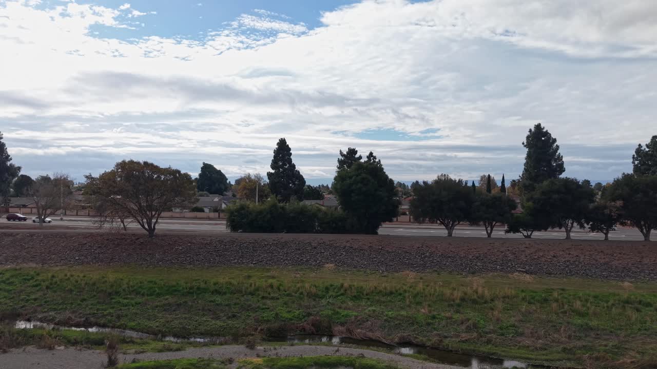 Rising drone shot reveals Fremont’s layered scenery: homes, parks, and creekside foliage surrounding the trail, forming a peaceful coexistence between community living and outdoor recreation