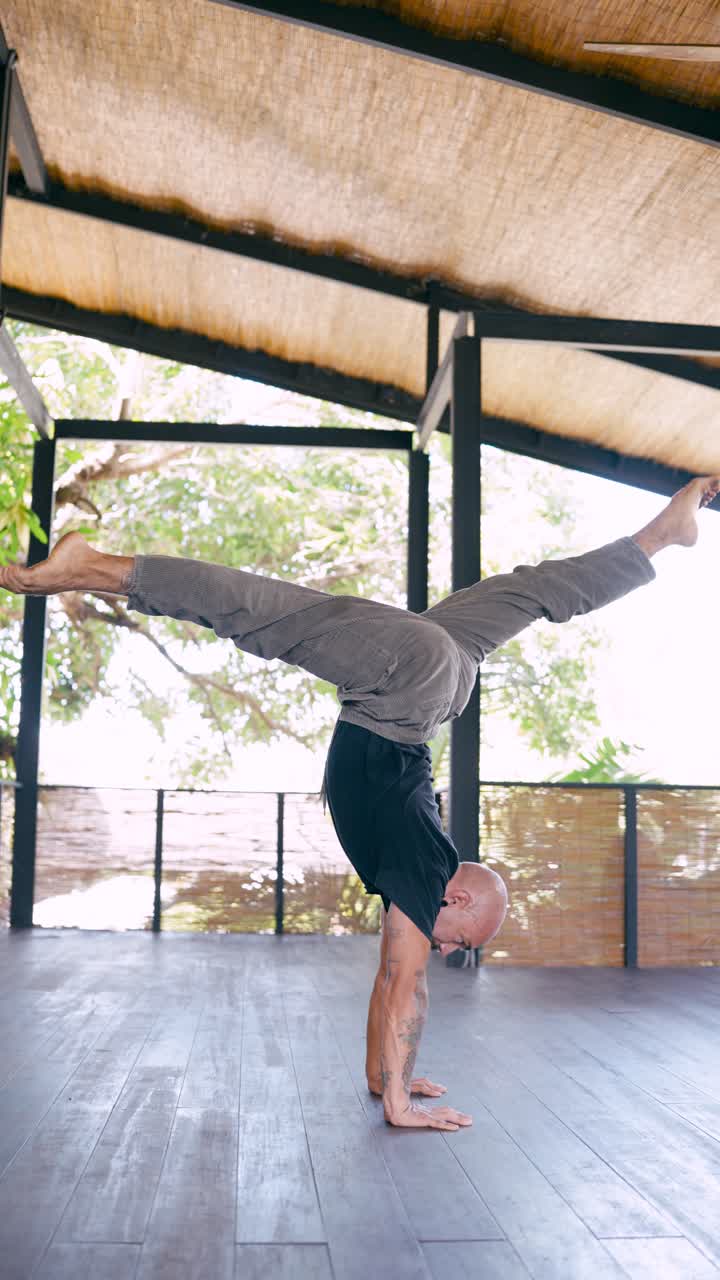 Man Performing Handstand with Leg Variations in Open-Air Studio