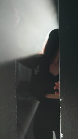 dramatic portrait of a woman in a black outfit, partially visible with a radiant backlight shining as the camera zooms out