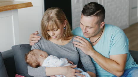 young couple resting at home with the baby in her arms