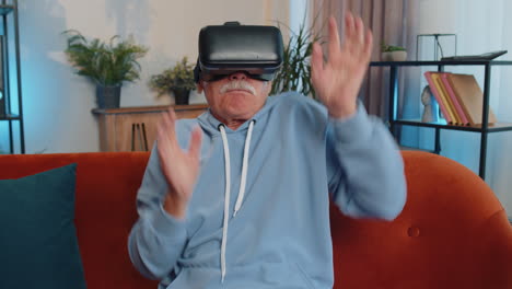 Senior-man-using-virtual-reality-futuristic-technology-headset-play-simulation-3D-video-game-at-home