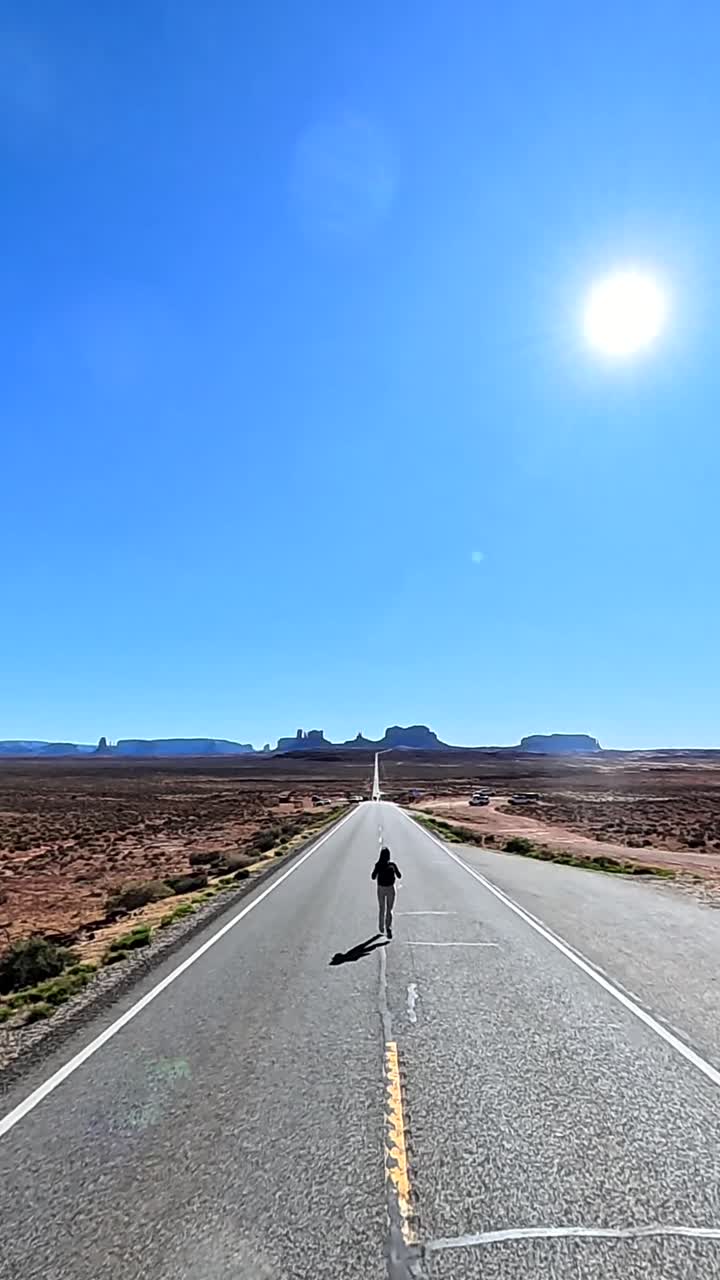 Mujer corriendo en una larga carretera desértica hacia montañas distantes