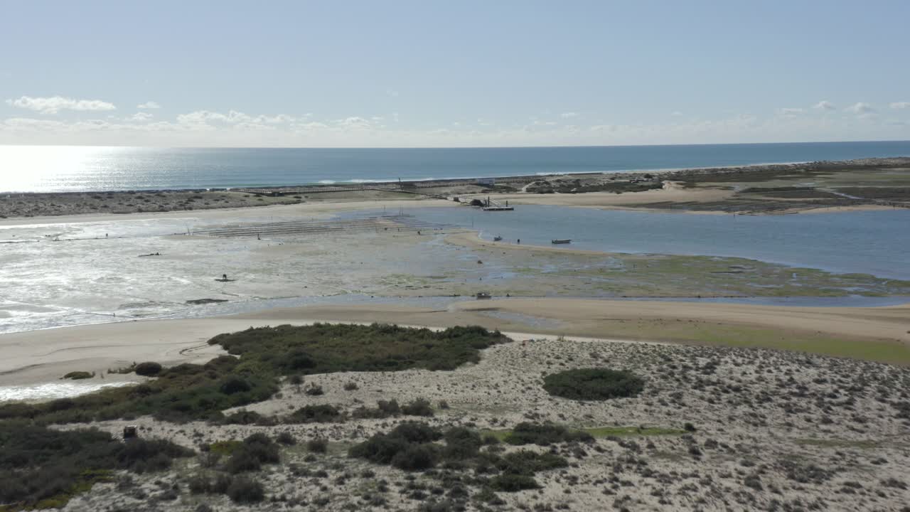 pescadores que trabajan en la playa mientras las olas chocan contra la playa en la isla de fuseta, portugal