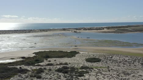 Fischer-Arbeiten-Am-Strand,-Während-Die-Wellen-Auf-Den-Strand-Der-Insel-Fuseta-In-Portugal-Stürzen