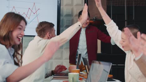 happy ceo indio, jefe empresario cuenta grandes noticias al equipo en la reunión de mesa de la oficina, celebran el éxito en cámara lenta.