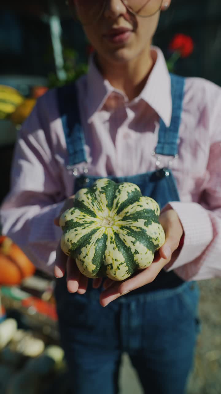 시장 에서 작은 호박 을 들고 있는 젊은 여자
