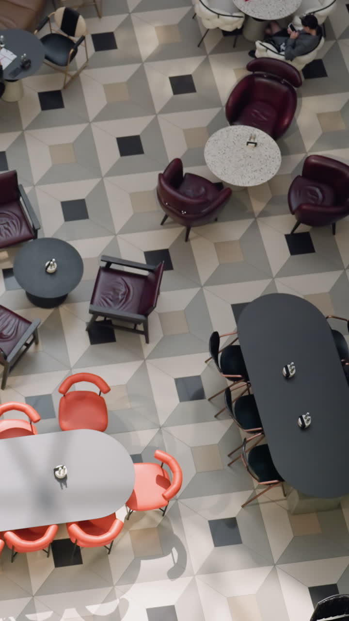 물 분수, 다양한 테이블, 의자, 그리고 다양한 활동에 종사하는 사람들이 있는 바쁜 쇼핑몰 카페 지역의 상공 전망