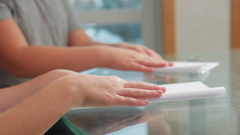close-up of hands of kids carefully folding white paper on the table, working on a creative craft project, focus on hands and paper while kids engage in craft activity indoors