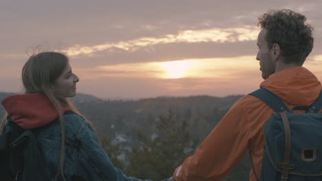 hermosa puesta de sol joven pareja de excursionistas en la cima de la montaña cerca