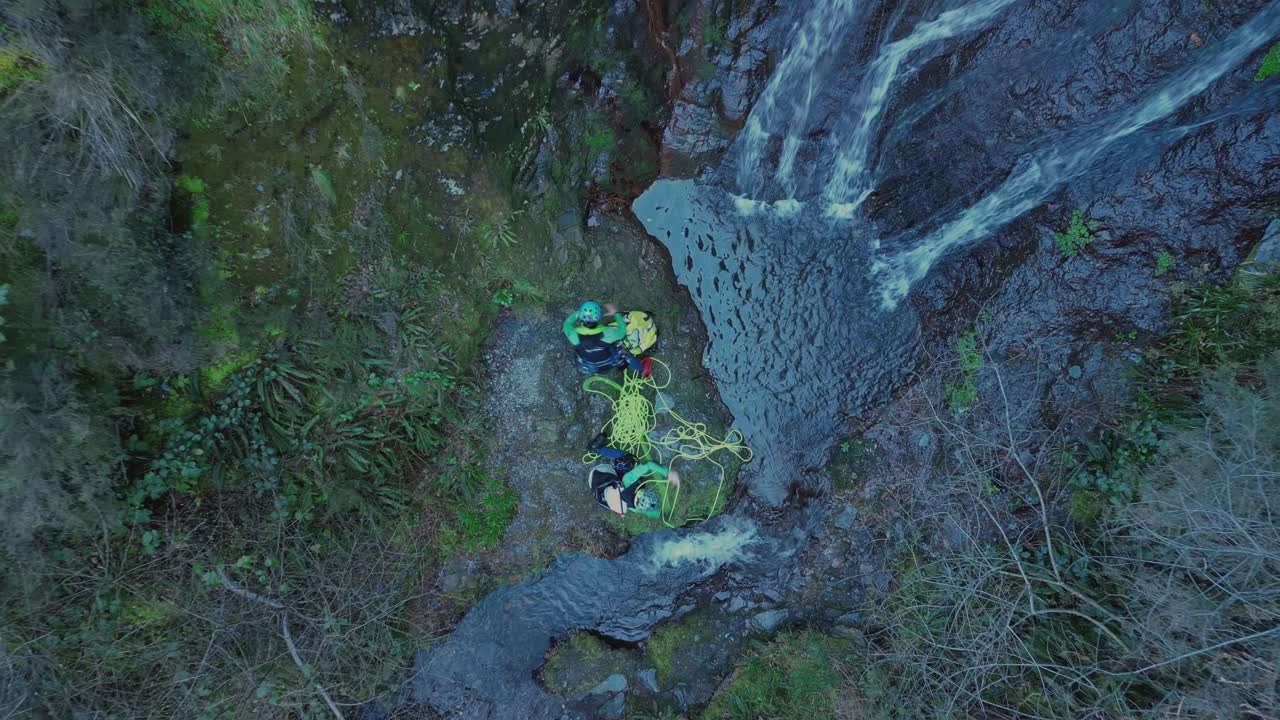 Mountaineers Preparing The Ropes For Climbing By The Waterfall. - aerial overhead shot