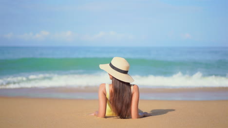 mujer tendida en la playa de arena, mirando las olas en cámara lenta