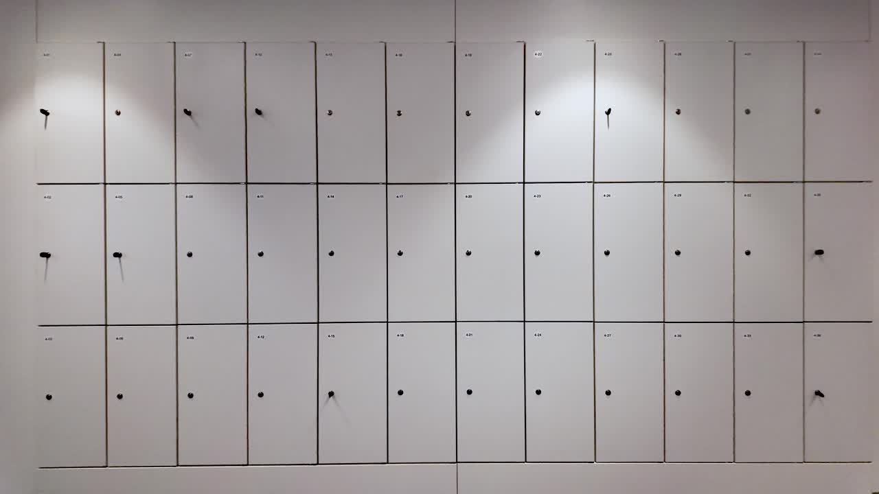 Wall of numbered office lockers, some showing keys and keyholes, providing secure storage for employees