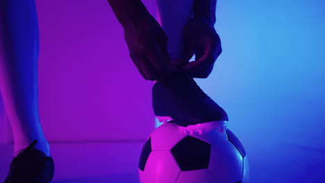 Close-up-of-black-african-male-soccer-player-tying-shoelace-on-studio-slow-motion.-Footballer-tying-his-shoe.-Low-section.-tying-football-boots-preparing-for-a-football-soccer-match