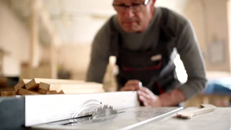 carpenter adjusting electric circular saw fo cutting piece of wood