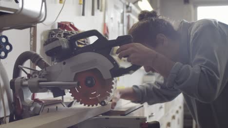 caucasian woodwork artisan cutting wood plank on miter saw