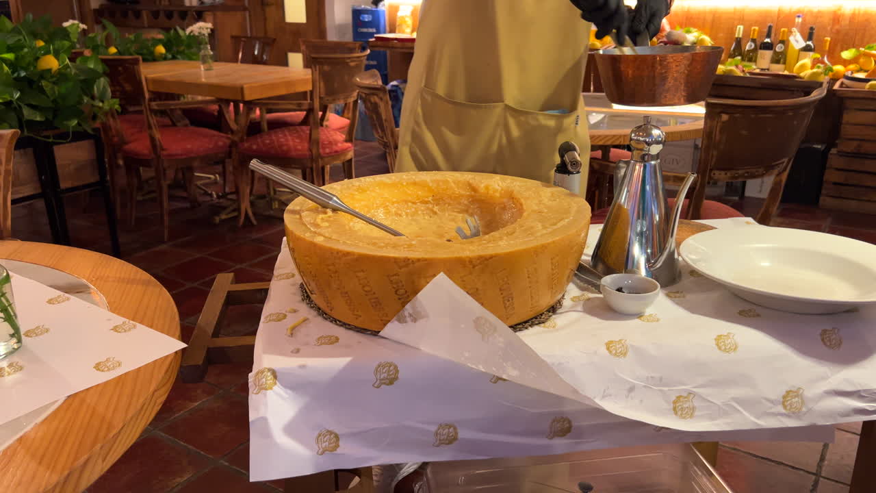 Preparing traditional Italian parmesan cheese wheel pasta dish at a restaurant, delicious fresh spaghetti, food in Italy, 4K shot