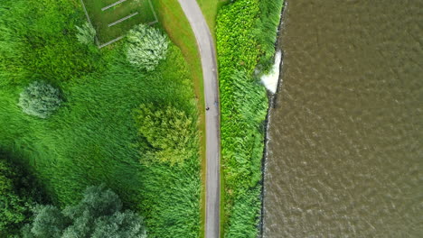 two people enjoying walking on pathway at the park around a lake in reeuwijkse plassen, reeuwijk, zuid-holland, the netherlands