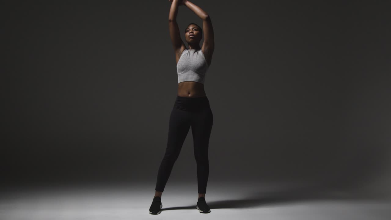 Studio Shot Of Young Woman Wearing Gym Fitness Clothing Warming Up For Exercise 3