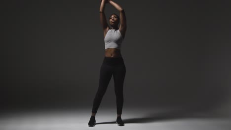 Studio-Shot-Of-Young-Woman-Wearing-Gym-Fitness-Clothing-Warming-Up-For-Exercise-3