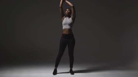 studio shot of young woman wearing gym fitness clothing warming up for exercise 3