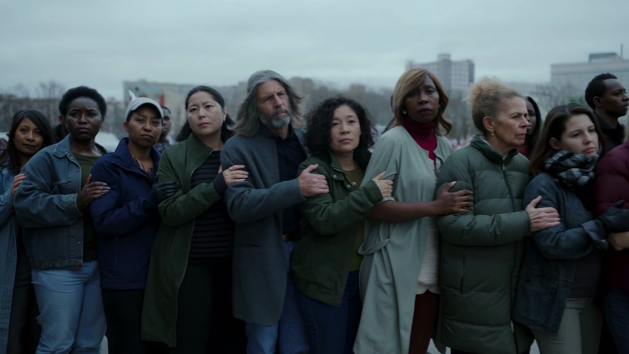 Diverse Crowd Linking Arms On Rooftop, Somber Urban Skyline, Varied Adults And Seniors Shouldertoshoulder