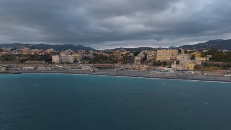 Genoa-coastline-with-historic-architecture-and-choppy-sea,-overcast,-aerial-view