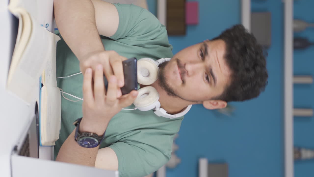 video vertical de un estudiante masculino usando el teléfono mientras baila.