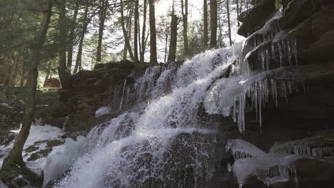 rosecrans falls waterfall with ice formations in a forest in central pennsylvania, pan downward