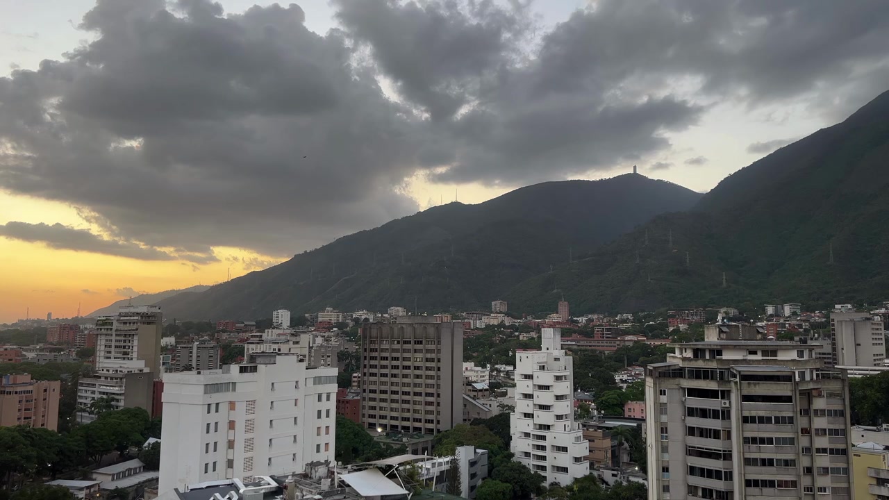 Gün batımında Caracas şehrinin, Avila Milli Parkı ve dramatik bulutlarla panoramik görüntüsü.