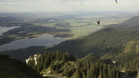 Person-Gleitschirmfliegen-Mit-Dem-Instruktor-In-Den-Deutschen-Alpen