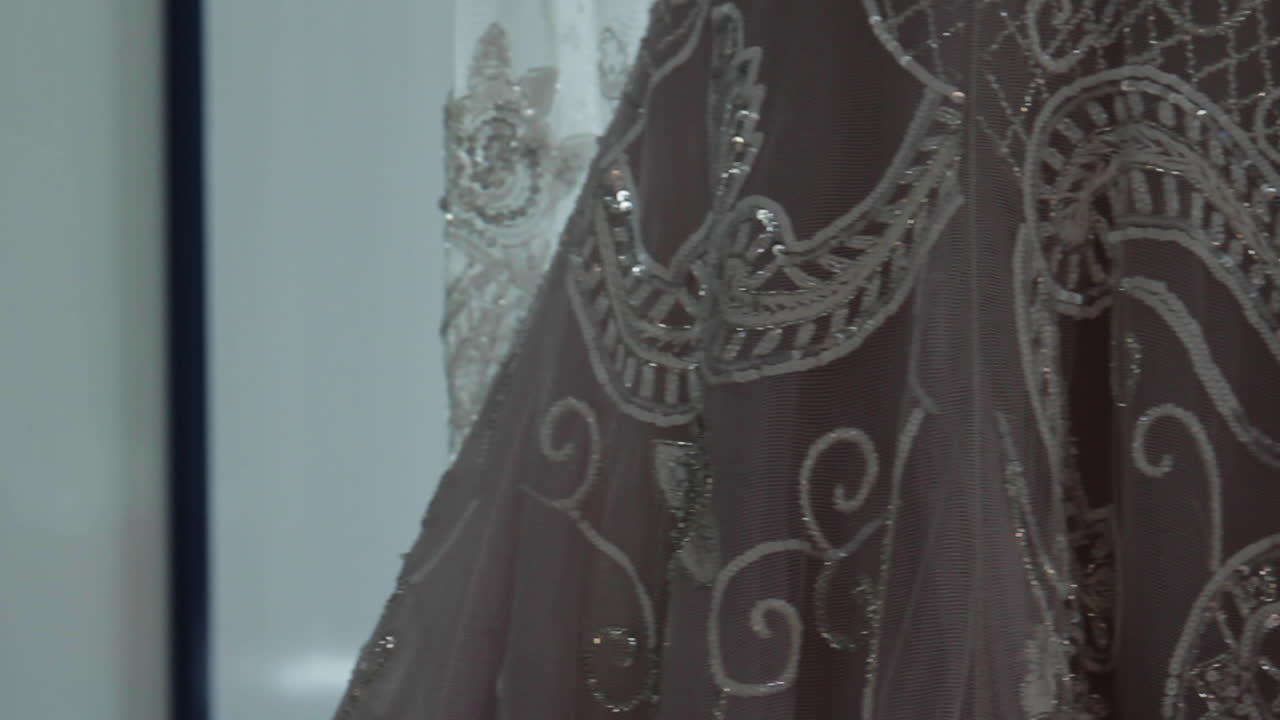 vestido de novia colgado cerca de una ventana brillante en el lugar de la boda