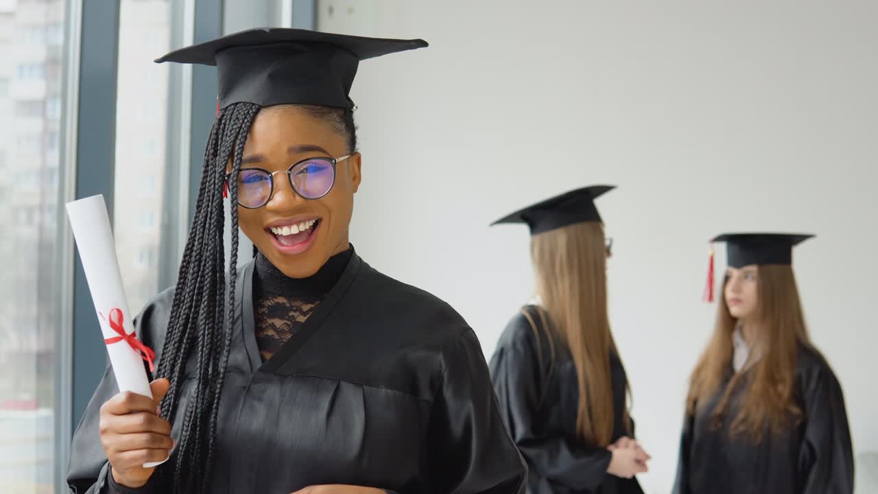 un graduado alegre con un diploma en la mano se encuentra en la universidad en el fondo de los graduados hablando entre sí. programa de intercambio de estudiantes entre universidades de todo el mundo
