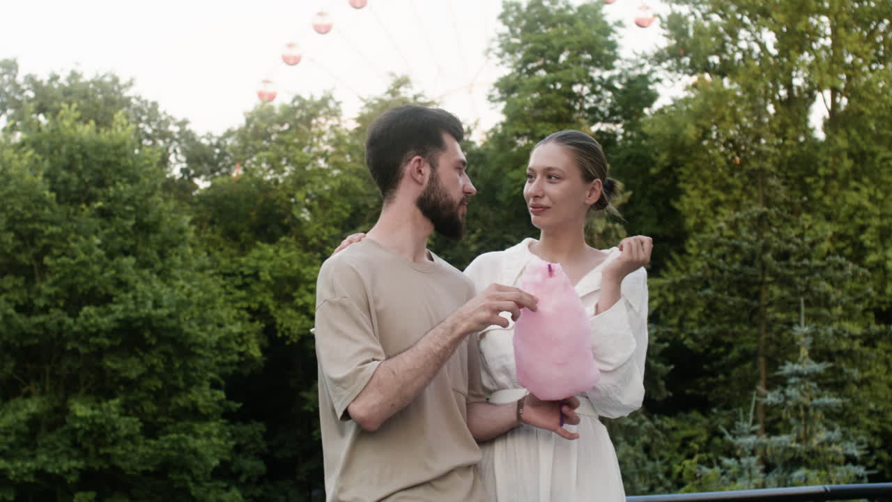 맛있는 목화 사탕을 먹는 젊은 부부