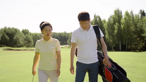 Asian-couple-talking-and-walking-throung-golf-field