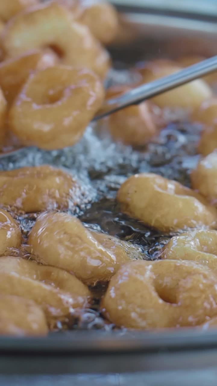 Ciambelle dorate che friggono in olio bollente e frizzante