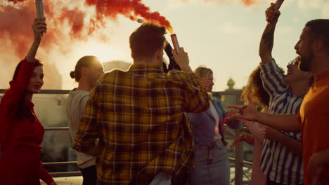 partying friends having fun with smoke bombs at rooftop. friends enjoying party