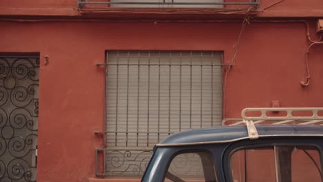 vertical shot of a small balcony, potted plants, car and an orange painted wall