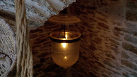 Hanging-plant-pots-on-nets-and-pendant-light-fixture-among-rustic-architecture-arches-in-Southern-France,-Dolly-in-shot