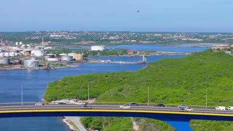 Retirada-Y-Panorámica-Del-Dron-A-Través-Del-Puente-Reina-Juliana,-Willemstad-Curacao-Y-La-Refinería-De-Petróleo