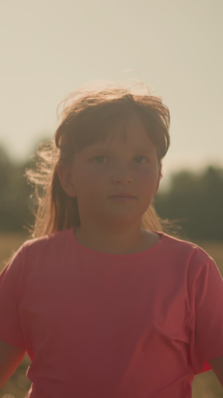 close up de una niña caminando estrechamente entre dos adultos, sosteniendo sus manos mientras se mueven a través de un vasto campo de hierba en un día soleado, el fondo presenta árboles ligeramente borrosos