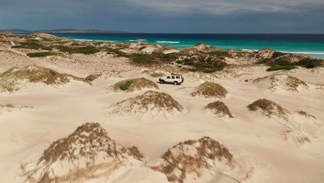 4wd car driving across sand dunes on the coast, australia, aerial view