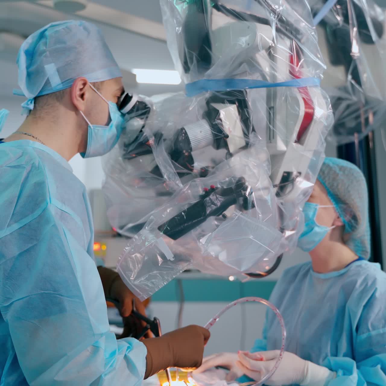 Male surgeon doing microscopic surgery. Doctor and assistant use a surgical microscope in the operating room. Innovative technologies in medicine.