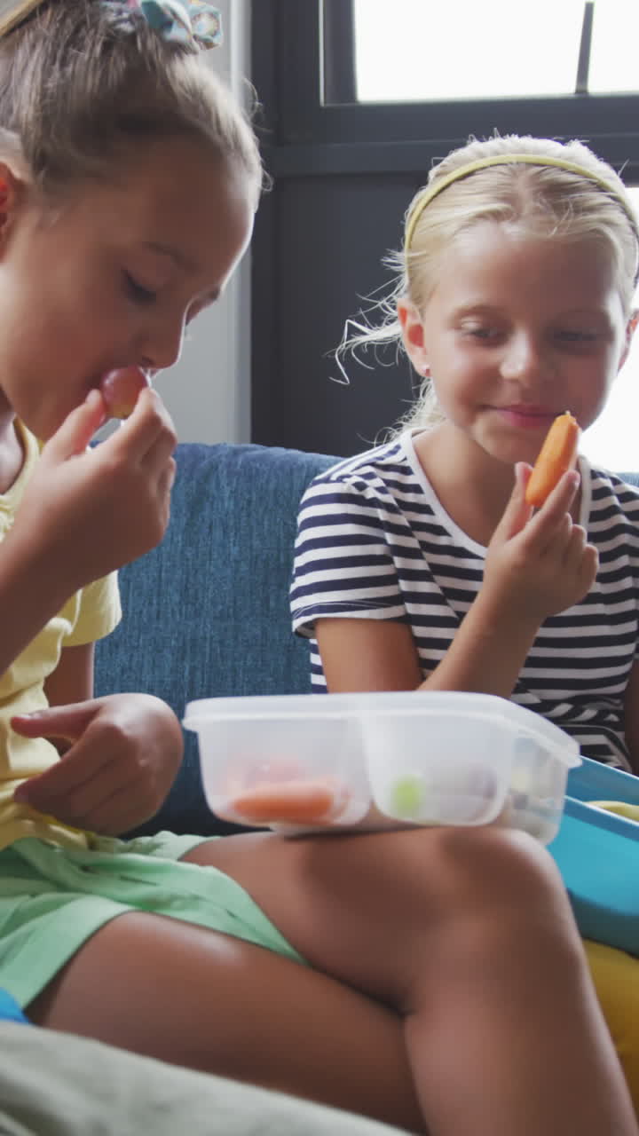 video de niñas felices y diversas sentadas en la sala común de la escuela con cajas de almuerzo y comiendo