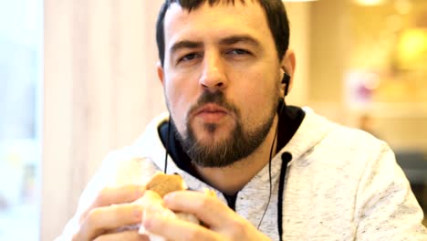 young man is enjoying a delicious burger and smiling at the camera.