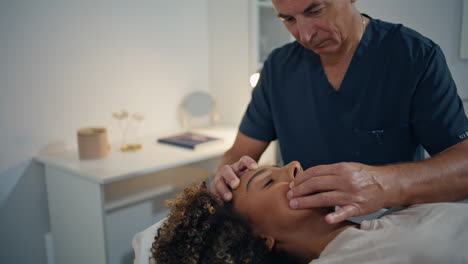 osteopath massiert den kopf in der station. reife physiotherapeutin heilt eine frau