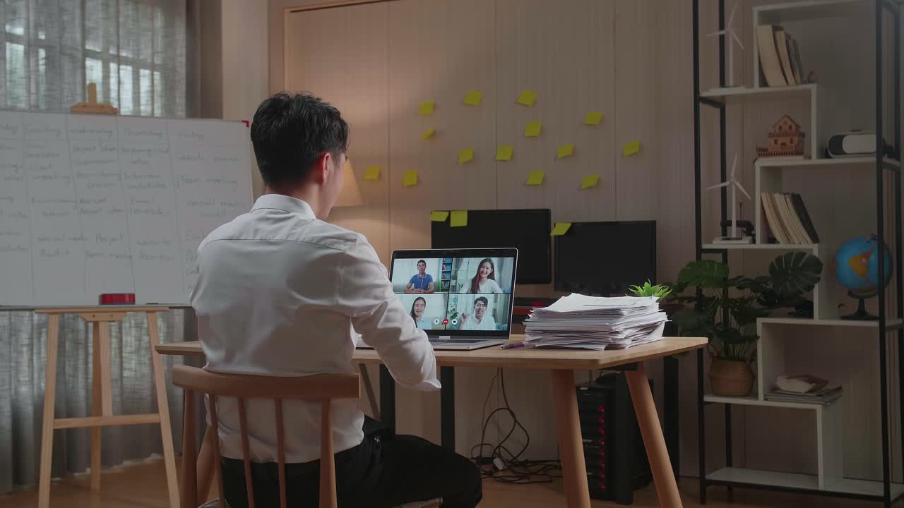 사무실 에서 문서 를 처리 하는 동안 노트북 으로 비디오 통화를 하는 아시아인 의 뒷면
