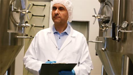 cervecero manteniendo un registro en el clipboard en la fábrica de cerveza
